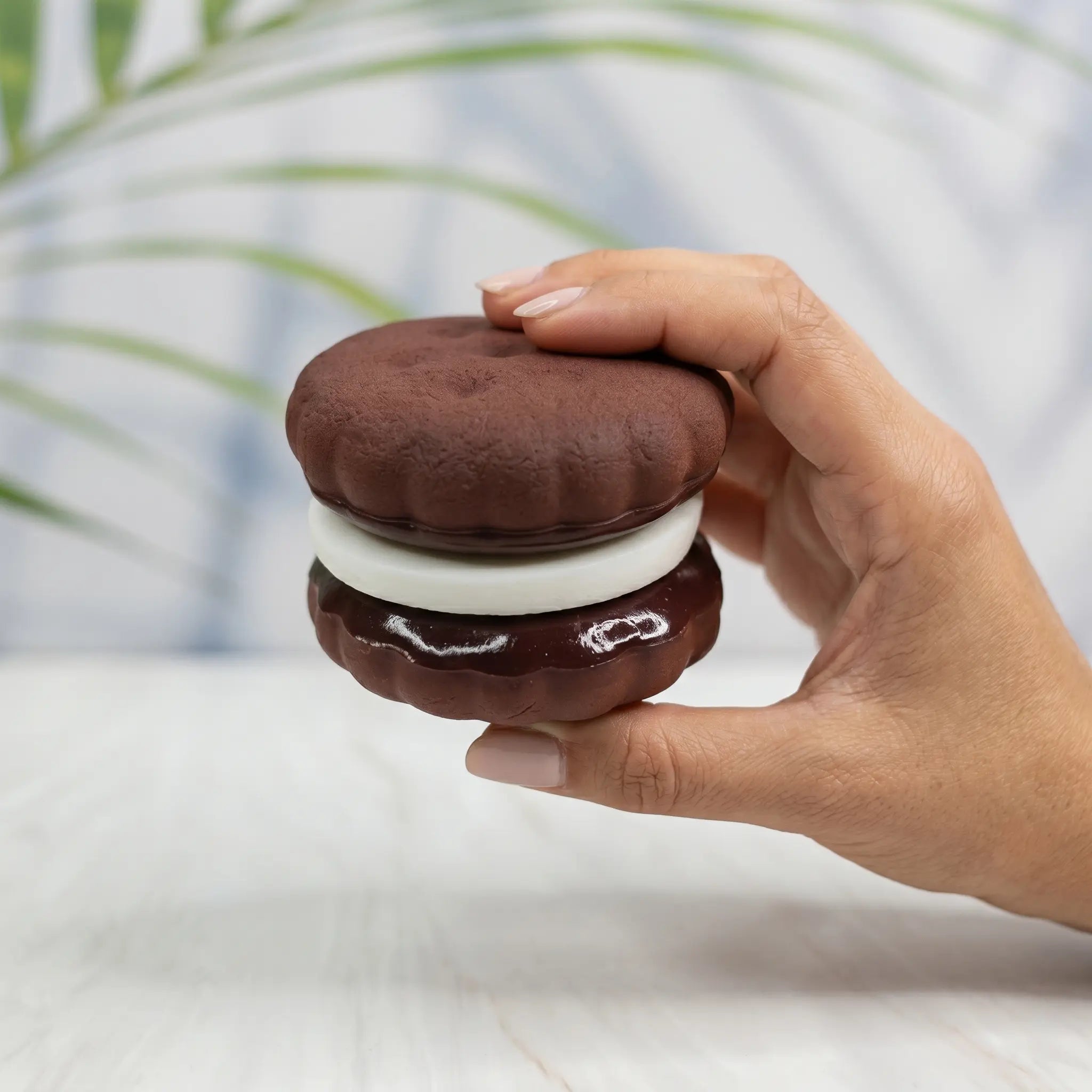 Chocolate macaron squishy displayed in a hand