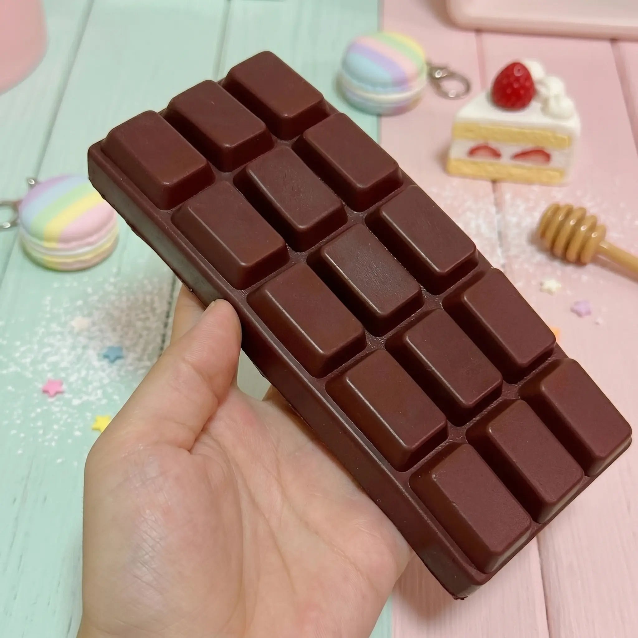 Dark chocolate bar squishy displayed on a rustic wooden surface surrounded by dark chocolate pieces