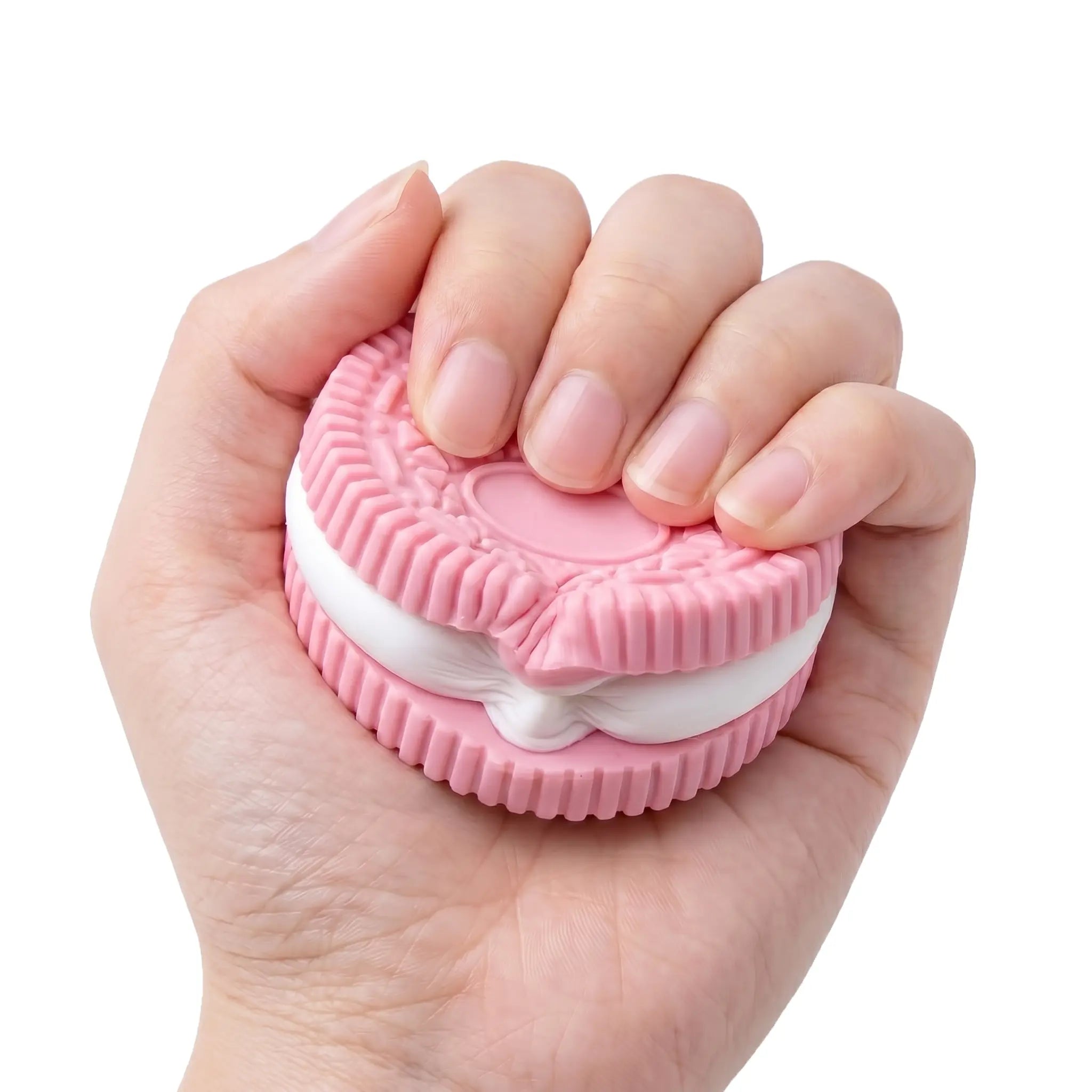 A hand squeezing a Pink Cookie showing its slow rising soft texture for stress relief.