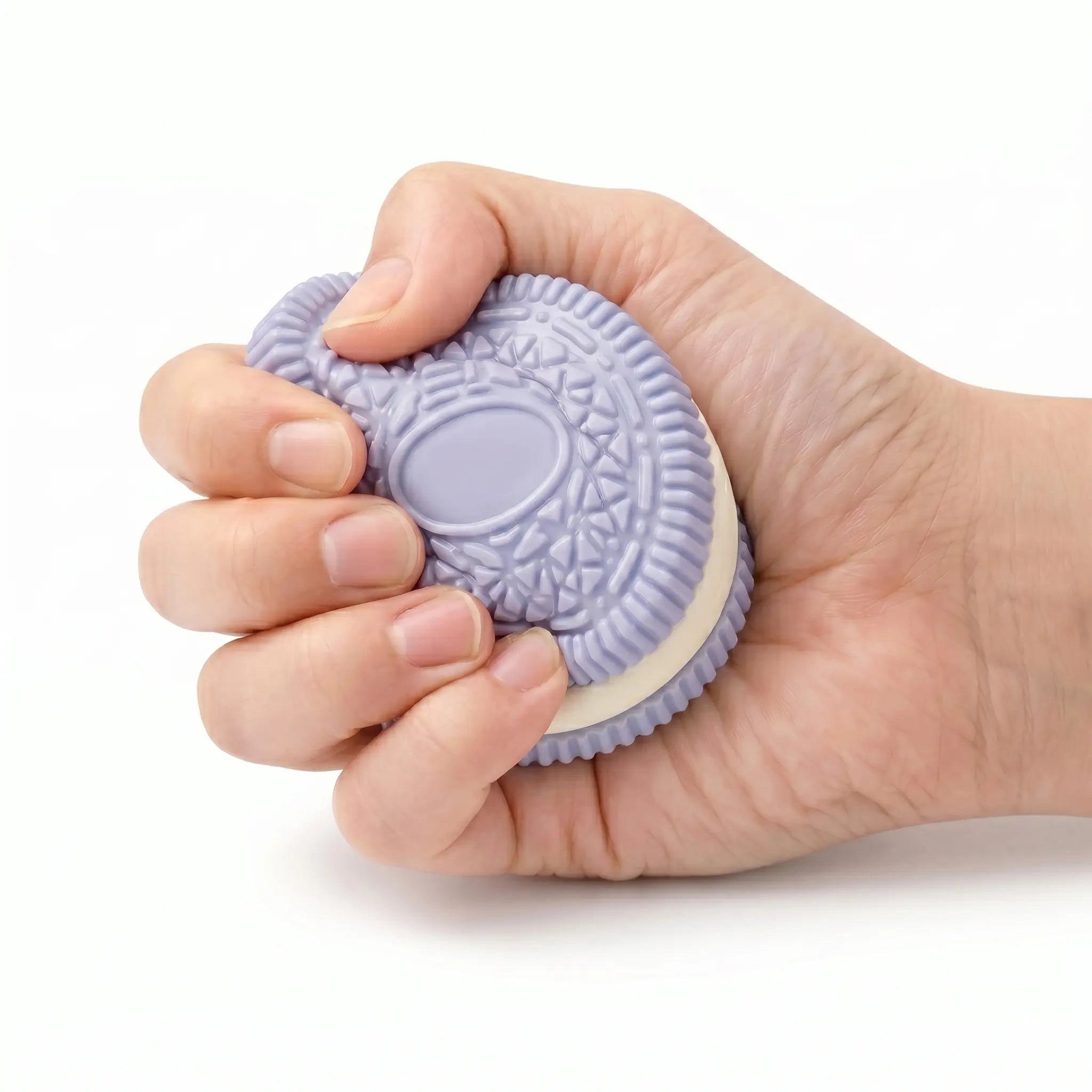A hand squeezing a Purple Cookie showing its slow rising soft texture for stress relief.